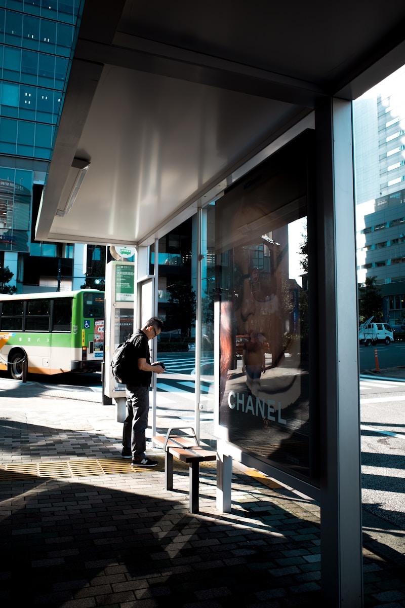 A man standing at a bus stop waiting for a bus